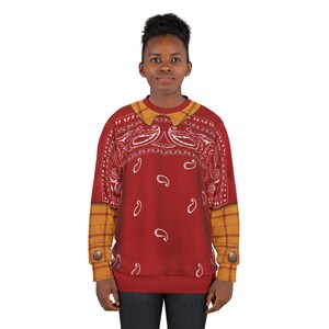 May include: A long-sleeve sweatshirt featuring a red bandana paisley print on the chest and back, with a mustard yellow plaid collar and sleeve cuffs. The cuffs include a single brown button detail on each side, creating a layered appearance.