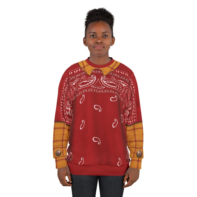 May include: A long-sleeve sweatshirt featuring a red bandana paisley print on the chest and back, with a mustard yellow plaid collar and sleeve cuffs. The cuffs include a single brown button detail on each side, creating a layered appearance.