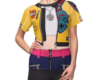 May include: A yellow crop top with a black zipper and a design that resembles a jacket. The top has a white undershirt and a silver necklace. The model is also wearing a pink and blue belt with zippers.