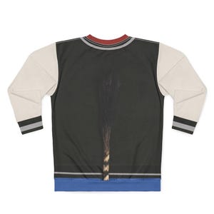 May include: A black sweatshirt with cream-colored sleeves. The sleeves have a black and gray stripe at the wrist. The neckline has a red and gray stripe. The front of the sweatshirt has a dark image of a plant.