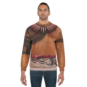May include: A long-sleeve crewneck sweatshirt featuring a realistic printed design of a tan-coloured chest with a dark red and white tooth necklace, black tribal arm tattoos, and a patterned fabric wrap around the waist in shades of red and white.