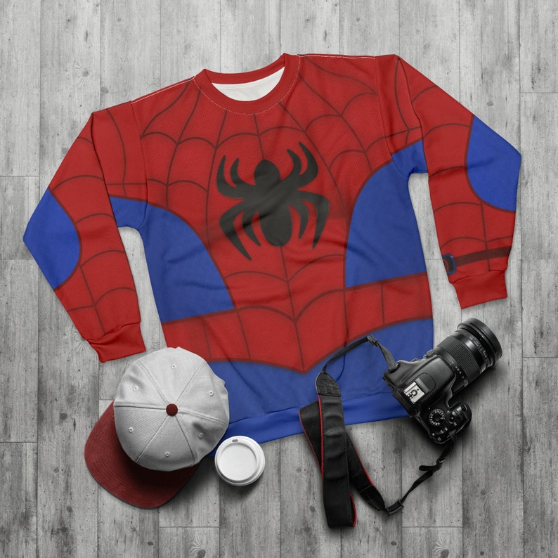 May include: Red and blue sweatshirt with a spider web design and a black spider in the centre. The sweatshirt has long sleeves and a crew neck.