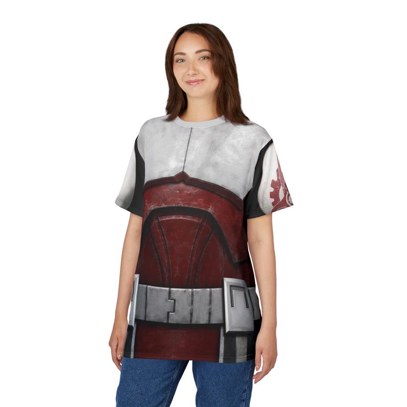 May include: A t-shirt with a design that mimics armour, in white, red, and grey. The design includes a chest plate, shoulder details, and a belt-like feature. The shirt is worn by a person wearing blue jeans.