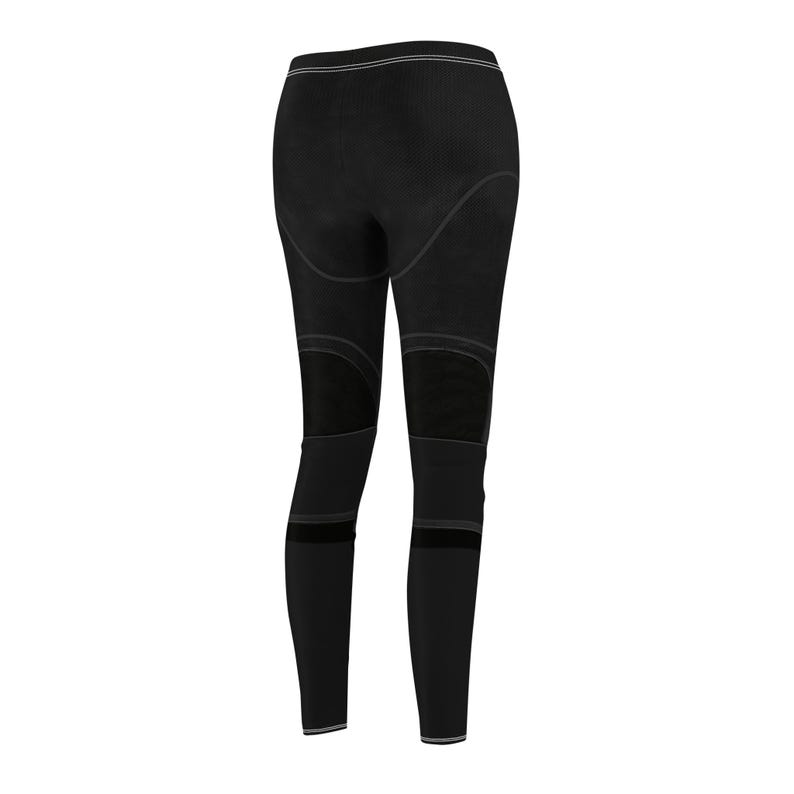 Puede incluir: Mallas deportivas negras con paneles de malla en los muslos y la parte inferior de las piernas. Las mallas tienen una cintura alta con una fina raya de color claro y una raya similar en los tobillos. El dise&ntilde;o general es elegante y moderno.