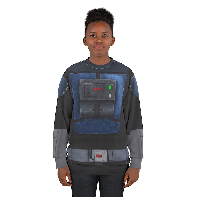 Puede incluir: Una sudadera negra y gris con un dise&ntilde;o azul y gris que se asemeja a un uniforme futurista. El dise&ntilde;o incluye un panel rectangular con detalles rojos y verdes y un dise&ntilde;o de cintur&oacute;n gris en la cintura. La sudadera la lleva una persona.