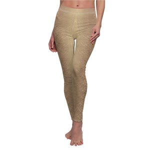 May include: Tan leggings with a textured pattern. The leggings have a high waist and a form-fitting design. The fabric appears to have a subtle, organic texture, creating a unique visual effect. The leggings are a neutral colour, suitable for various outfits.