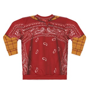 May include: A long-sleeve sweatshirt featuring a red bandana print with white paisley patterns across the chest and back. The garment includes a yellow and brown plaid pattern on the sleeves and a matching plaid collar detail at the neckline.