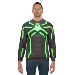 Op de afbeelding: Een donkergrijs sweatshirt met een neon groen geometrisch ontwerp over de borst en schouders. De longsleeve heeft een ronde hals en wordt gedragen door een persoon in een blauwe jeans.