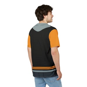May include: A black t-shirt with orange and gray accents. The shirt has a graphic design on the back.