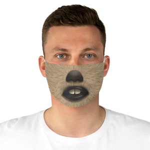 May include: A person wearing a face mask with a brown and black furry animal face printed on it. The mask has a black nose and mouth with white teeth.