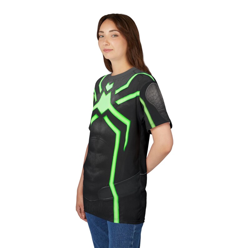Peut inclure: T-shirt noir avec un motif en forme d'araign&eacute;e vert fluo sur le devant et les manches. Le t-shirt a un aspect textur&eacute; et est port&eacute; avec un jean bleu.