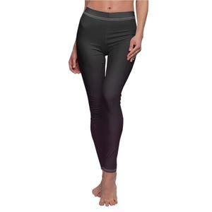 May include: Dark grey leggings with a gradient effect, fading to purple. White stitching details the waist and ankles. The leggings are made of a smooth, form-fitting fabric. The overall design is sleek and modern.
