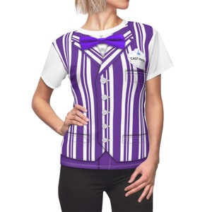 May include: A white t-shirt with a purple and white striped vest printed on it. The vest has a bow tie and a button-up front. The shirt also has a blue name tag that says "Cast Member".