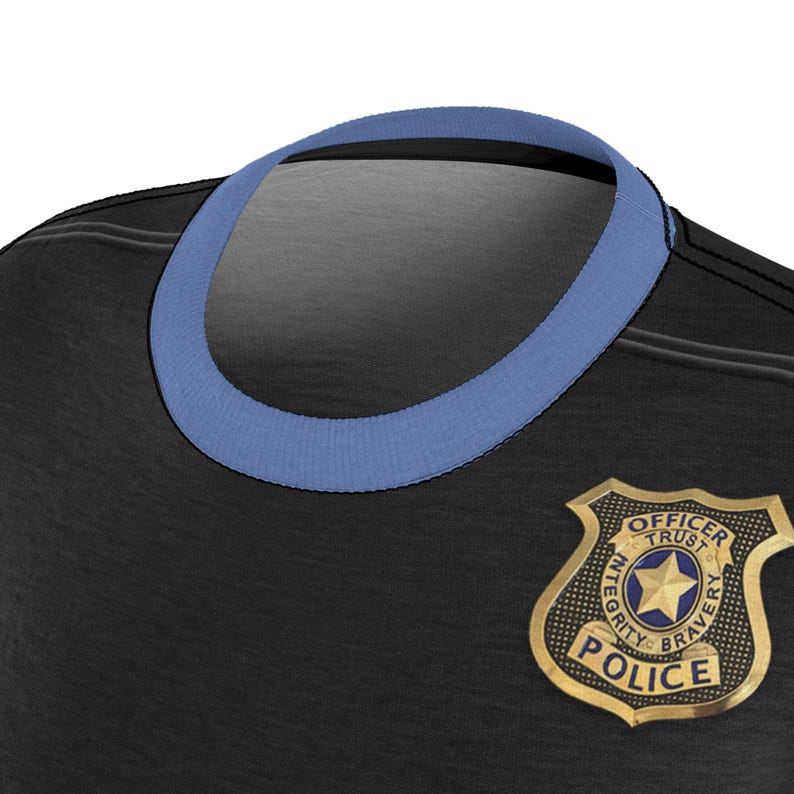 May include: Close-up of a black t-shirt with a light blue collar. A gold-colored police badge is visible on the shirt, featuring the words "Officer Trust Bravery Police" and "Integrity".