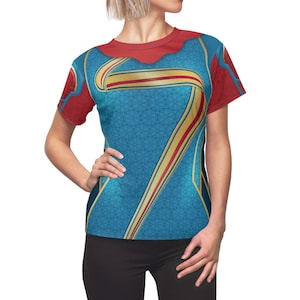 Op de afbeelding: Een blauw, rood en gouden T-shirt met korte mouwen met een geometrisch patroon en een groot nummer zeven ontwerp.