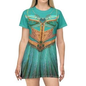 Pode incluir: Um vestido de camiseta azul turquesa com uma estampa dourada e verde de um traje de princesa. O vestido tem manga curta e decote redondo.