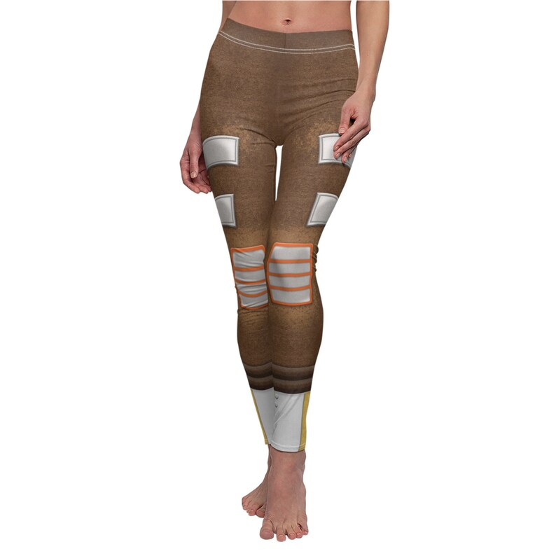 May include: Brown leggings with white and orange accents. The leggings have a textured fabric design and resemble a pair of boots.