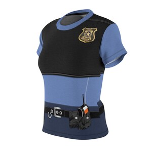 May include: A short-sleeved t-shirt designed to resemble a police uniform. The shirt features a black upper section with a gold-colored badge, a light blue lower section, and a black belt with accessories. A walkie-talkie is attached to the belt.