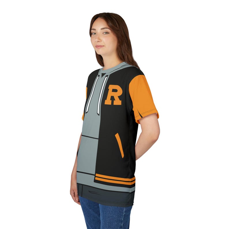 May include: A black and gray t-shirt with a graphic of a black and gray varsity jacket with orange sleeves. The jacket has a large gray letter "R" on the front.