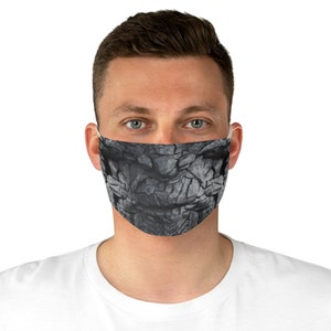 May include: A black and gray face mask with a cracked stone texture design.