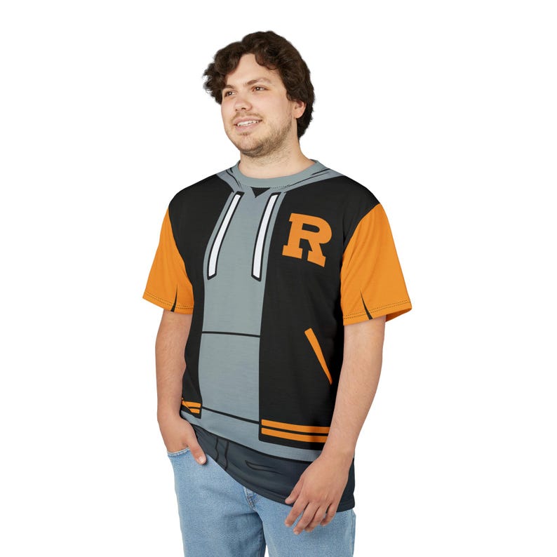 May include: A black and gray t-shirt with a graphic of a black and gray jacket with an orange and white stripe. The jacket has a gray hoodie with white drawstrings and a white letter "R" on the right side.