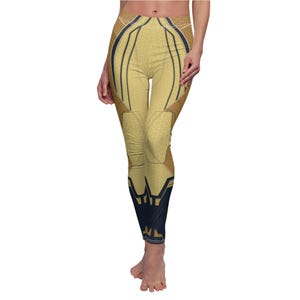 May include: Gold and navy blue leggings with a geometric design. The leggings feature a textured gold pattern with navy blue and brown accents. The design includes lines and shapes, creating a unique look. The leggings are form-fitting.