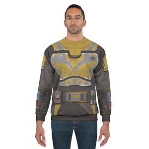May include: A grey and yellow sweatshirt with a detailed armour-like design. The design includes a yellow chest plate, grey accents, and a belt with a buckle. The sleeves have additional details, and the overall look is reminiscent of a futuristic or sci-fi theme.