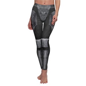 May include: Black leggings with a detailed print resembling armor plating. The design features shades of gray and black, creating a realistic, textured appearance. The leggings extend to the ankles.