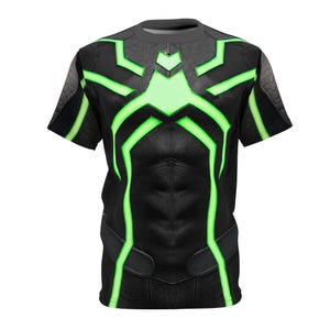 Peut inclure: T-shirt noir avec un motif textur&eacute; et des accents vert n&eacute;on. Le t-shirt pr&eacute;sente un motif g&eacute;om&eacute;trique sur la poitrine et les &eacute;paules, avec un design qui ressemble &agrave; un costume de super-h&eacute;ros. Le t-shirt &agrave; manches courtes a un col rond.