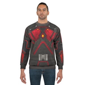May include: A gray sweatshirt with a red and black design resembling armor. The design includes geometric shapes, lines, and a belt-like detail across the midsection. The sweatshirt has long sleeves and a crew neck.