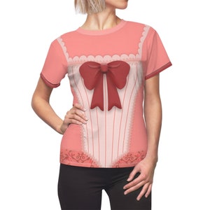 May include: A pink t-shirt with a white corset design and a large red bow. The corset has a lace trim and vertical lines.