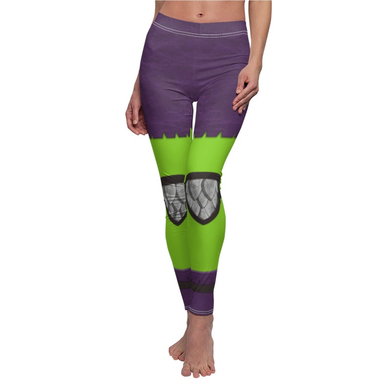 Puede incluir: Leggins morados y verdes con un estampado gr&aacute;fico de una criatura con escamas en las rodillas.