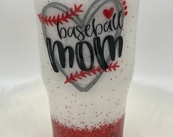 May include: White and red glitter tumbler with a gray heart design and the text "baseball mom".