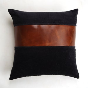 May include: Black velvet pillow with a brown leather band across the center.