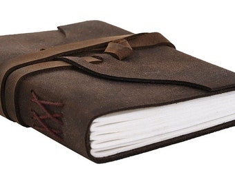May include: A brown leather journal with a strap closure and red stitching. The journal has blank pages and is closed.