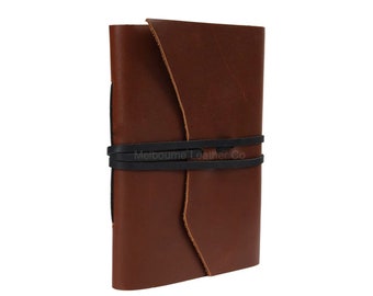 Könnte beinhalten: Ein braunes Lederjournal mit einem schwarzen Gummibandverschluss. Das Band trägt den Text "Melbourne Leather Co.".