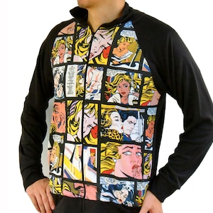 Pode incluir: Casaco preto com zíper e mangas compridas. A frente apresenta uma estampa colorida em estilo de história em quadrinhos com painéis de mulheres loiras, balões de fala e cores vibrantes. As mangas são pretas lisas.