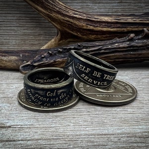 May include: Three silver rings with black bands and engraved text. The top ring reads "Self Be True Service". The middle ring reads "LYFEGOON". The bottom ring reads "God grant me the serenity to accept the things I cannot change".