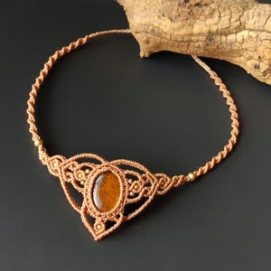 May include: A brown macrame necklace with a gold-toned oval tiger's eye gemstone pendant.