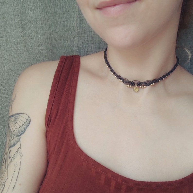 Woman wearing a small macrame choker with brass beads and charm
