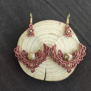 May include: A pair of brown macrame hoop earrings with a brown stone bead in each hoop.