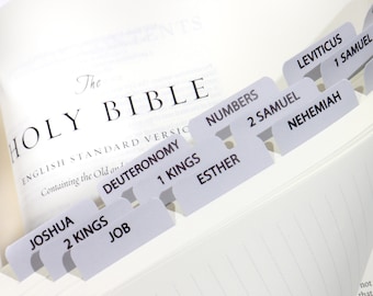 May include: A close-up of a white Holy Bible with gray tabs for each book of the Bible. The tabs are labeled with the book names, including Joshua, Deuteronomy, Numbers, 1 Kings, 2 Kings, Job, Esther, 1 Samuel, 2 Samuel, Leviticus, and Nehemiah.