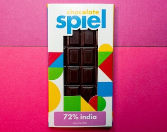 May include: A chocolate bar wrapper with a colorful geometric design. The wrapper is labeled "chocolate spiel" and "72% india". The bar is dark chocolate and has a net weight of 125g.