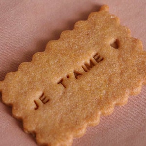 May include: A light brown cookie with the words "Je t'aime" embossed on the top.