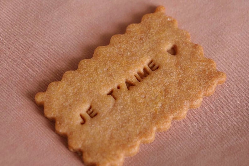 May include: A light brown cookie with the words "Je t'aime" embossed on the top.