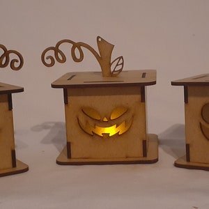 May include: Three wooden jack-o'-lantern candle holders with light brown paint and a carved jack-o'-lantern face. Each holder has a small stem with a leaf on top.