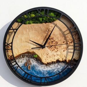 May include: A round wall clock with a black frame and Roman numeral markings. The clock face features a resin art design of a beach scene with blue water, white waves, and a sandy shore with two small boats. The top of the clock face has a patch of green moss.
