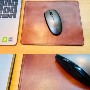 May include: Two brown leather mouse mats. The top mouse mat has a grey computer mouse with the word "Advent" on it. The bottom mouse mat has the word "Katrina" embossed on it and the text "Made with Split Pic" at the bottom right corner.