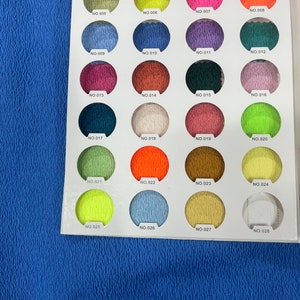 May include: A colour chart with 28 fabric swatches, each labelled with a number. The swatches are arranged in four rows of seven. The swatches are a variety of colours, including red, orange, yellow, green, blue, purple, and brown.
