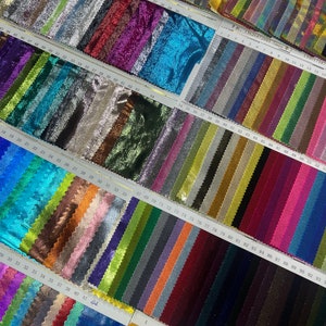 May include: A selection of fabric samples in diverse colours, such as silver, purple, teal, gold, and blue. Each swatch displays a unique shade and texture, organised in rows with numbered labels. The image includes text: 13626872885 (miss).